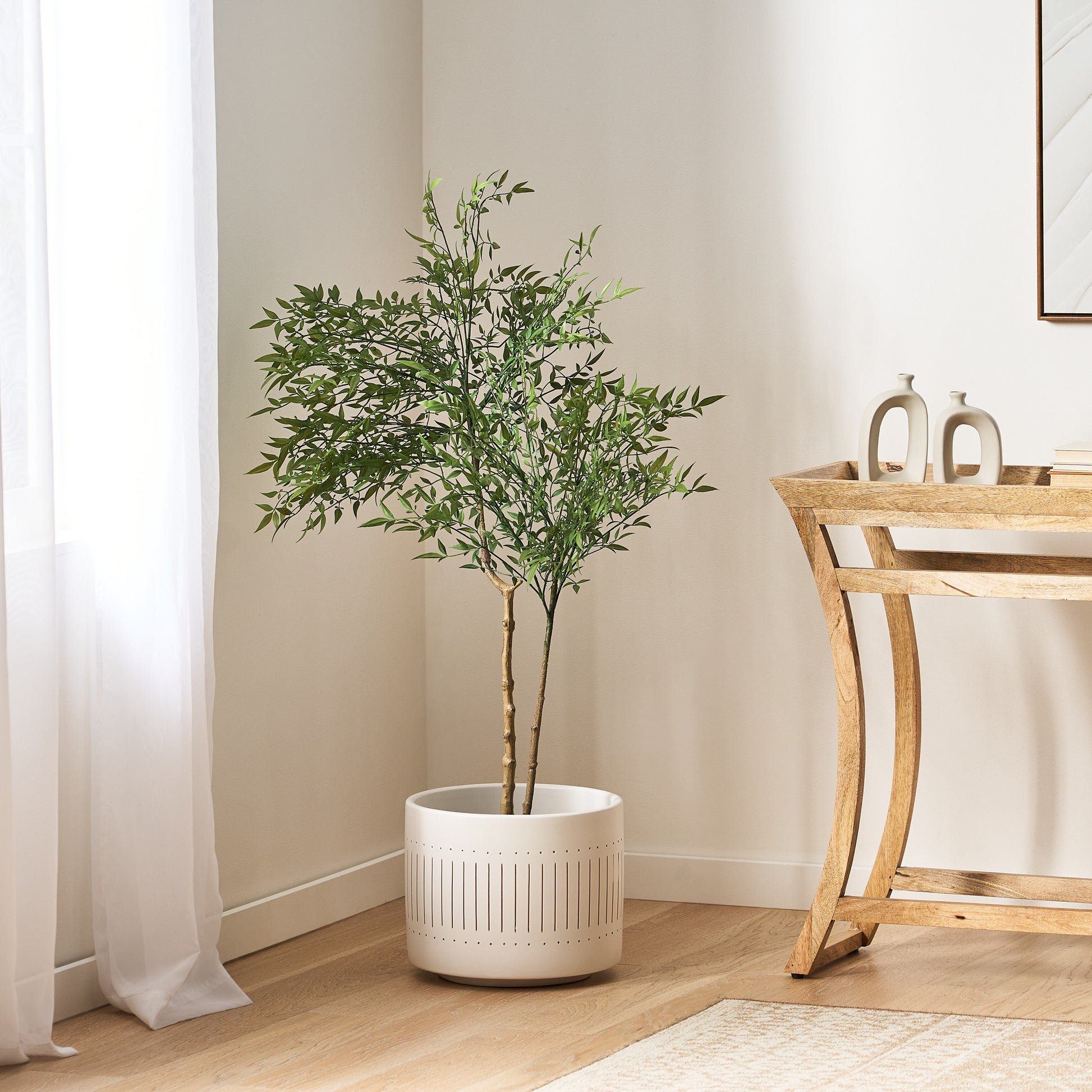 120CM ARTIFICIAL NANDINA in a white perforated planter indoors beside a wooden console table.