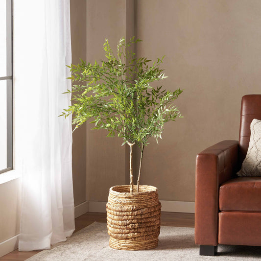120CM ARTIFICIAL NANDINA tree in woven basket, green polyethylene leaves beside a window