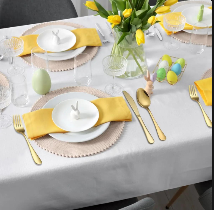 Gold-tone cutlery beside white plates and yellow napkins on a decorated dining table